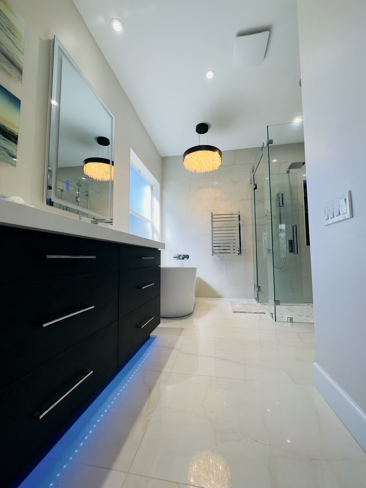 Frameless glass steam shower with marble tile and pendant chandelier, bathroom remodel by Line Flooring
